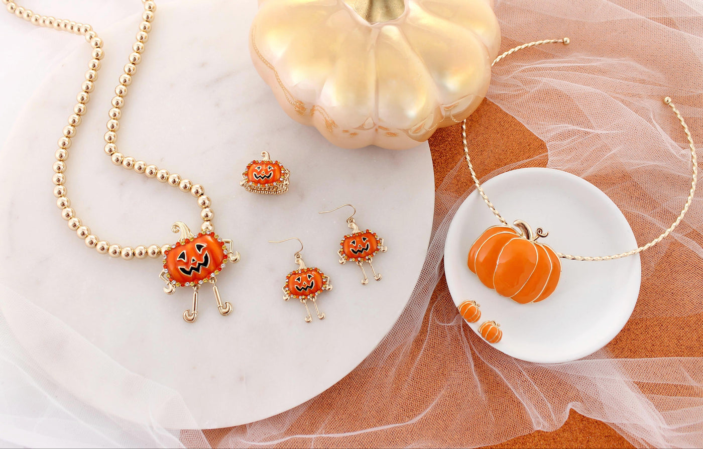 Halloween-themed jewelry set with pumpkin design on a white and orange fabric background