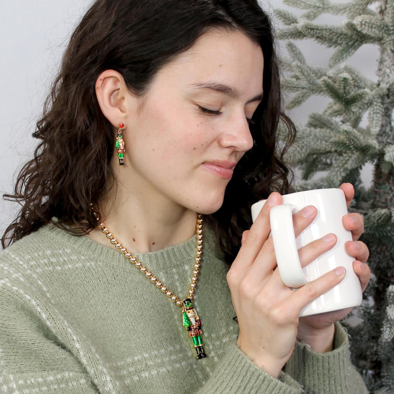 Woman holding a white mug with a Christmas tree in the background