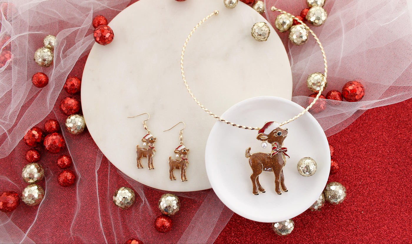 Reindeer-themed earrings on a white dish with red and gold decorative elements.